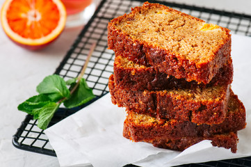 Slices of blood orange vegetarian pound cake on a wire rack. White stone background.
