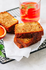 Slices of blood orange vegetarian pound cake on a wire rack. White stone background.