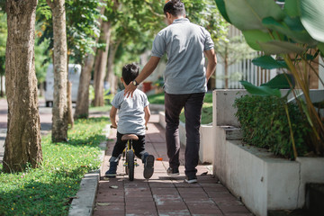 kid with his father learning how to ride a bicycle