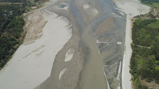 Mountain river Bucao flowing into the sea in Philippines,Luzon. Aerial view river among farmer fields flowing into the blue ocean.