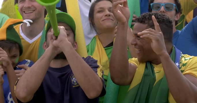 Brazilian football fans dancing and cheering at football match, slow motion