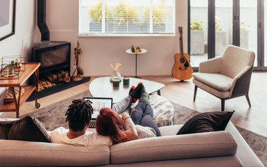 Couple sitting on sofa with laptop