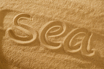 Word sea in the sand against the sun. concept symbol of holiday.