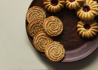 Biscuits or coocies with jam and sesame on dark plate on beige background, top view, copy space