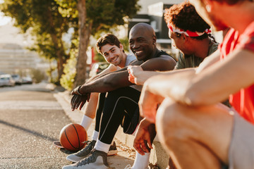 Fototapeta premium Basketball men sitting on the pavement and talking