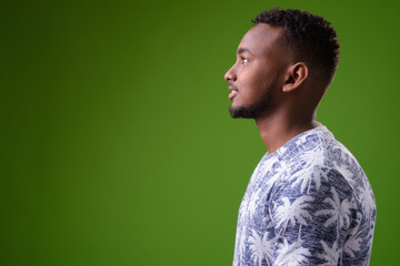 Young handsome African man against green background
