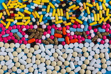 Fototapeta na wymiar Row White And Colored Pills On Blue Background, Top view. Creativity Medicine Concept