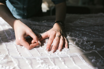 Women's hands sew the beads to the wedding dress