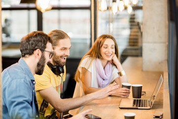 Happy colleagues with laptop in the cafe