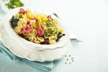 Colorful dried pasta in white bowl
