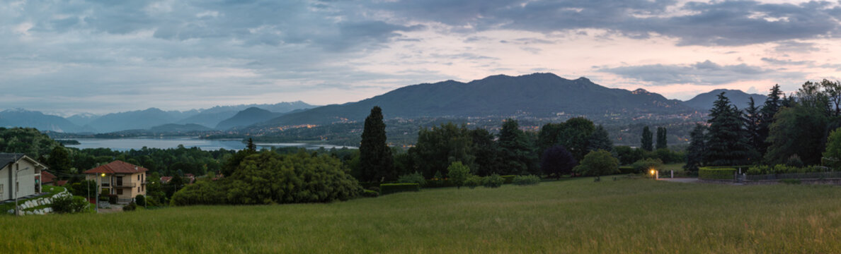 Province of Varese, Italy. Panoramic view at sunrise of the Varese lake, Mount Campo dei Fiori (regional park) and the Sacro Monte (UNESCO site). In the background the snow-covered Alps