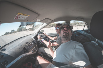 Adult couple selfie on road trip inside car, funny facial expression. Fisheye, people traveling and adventure, toned desaturated image.