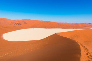 Fototapeta na wymiar Sossusvlei Namibia, clay and salt pan surrounded by majestic sand dunes. Namib Naukluft National Park, main visitor attraction and travel destination in Namibia.