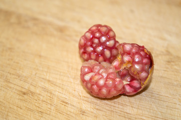 Ripe dwarf pomegranate fruit peeled on wooden surface close up, crop of punica granatum var. nana