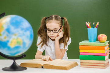 Girl with books preparing for the exam on the background of a school board