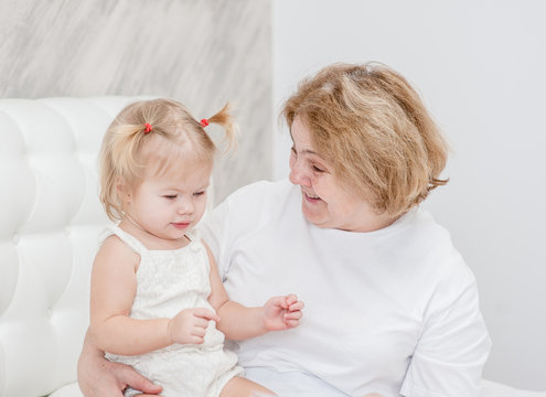 grandmother talking to her granddaughter on the bed