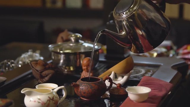 Tea ceremony. Tea maker pours boiling water into the teapot, slow motion