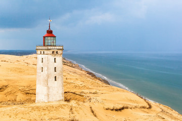 Fototapeta na wymiar Rabjerg mile a lighthouse on the Danish coast with storm clouds in the sky