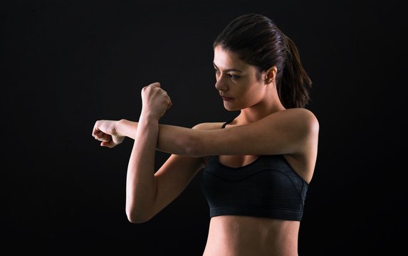 Young sport girl stretching on black background