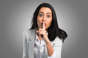 Pretty woman making silence gesture on grey background