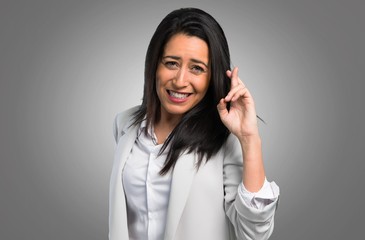 Pretty woman with her fingers crossing on grey background