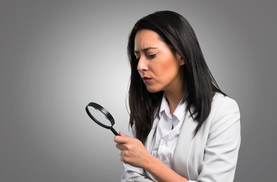 Pretty Woman With Magnifying Glass On Grey Background