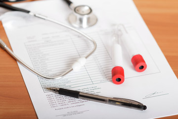 Test tubes for blood, phonendoscope, examination results on table