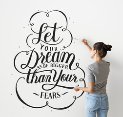 Female artist writing a life motivation quote on the wall