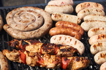 Sausages and chicken are cooked on the grill. Photographed under natural sunlight