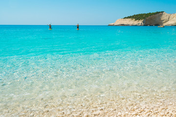 Obraz premium A couple is floating on a their SUP boards into the turquoise waters of Porto katsiki in Lefkada Ionian island in Greece