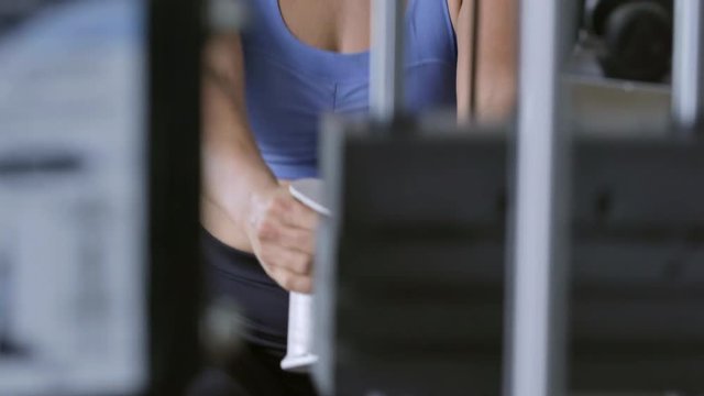 Fit young woman working out at the gym and performing rowing exercise using pulley machine with weight stack