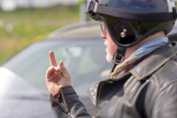 a biker shows his middle finger to a car driver