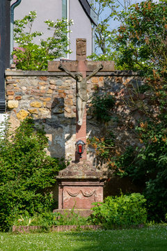 Big crucific in a garden in front of a old stony wall 