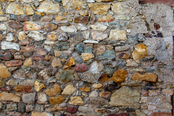 Surface of a brick wall with a lots of different stones 