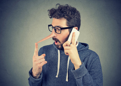 Surprised young man with long nose talking on mobile phone