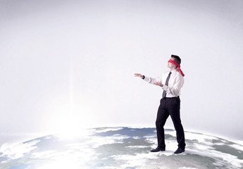 Young blindfolded businessman steps on a realistic globe