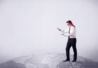 Young blindfolded businessman steps on a grey world map