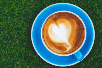 Hot coffee, cappuccino in a cup of blue coffee placed on grass