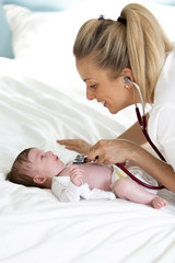 Obraz na płótnie Canvas Pediatrician examines baby with stethoscope at home