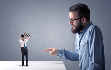 Young professional businessman being angry with an other miniature businessman in front of a...