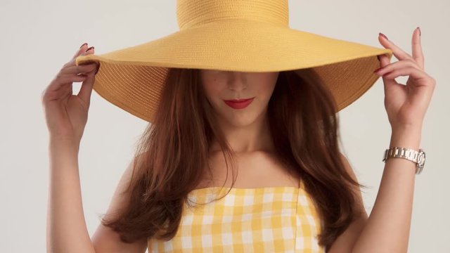 woman looks down wearing hat, no recognizible person, blowing hair bright lips