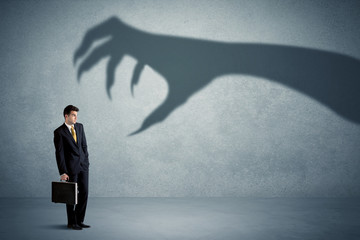 Fototapeta premium Business person afraid of a big monster claw shadow concept on background
