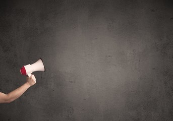 Caucasian arm holding megaphone with plain grunge background