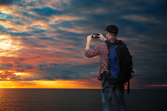  man is taking pictures of the sun setting on the sea
