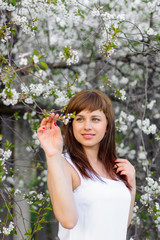brunette girl in white dress in spring on cherry blossom background