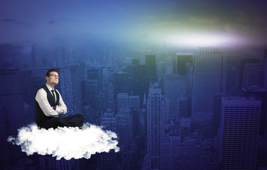 Caucasian businessman sitting on a white fluffy cloud above the city, thinking and wondering