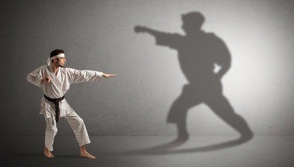 Fototapeta na wymiar Young karate man confronting with his own shadow 