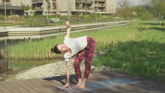 Glorious female practicing yoga on exercise mat in nature near house