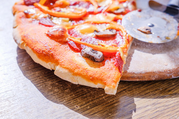 Cutting pepperoni pizza on slices with knife.