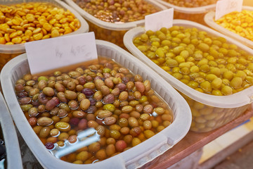 Green olives in containers, close up, olives on market